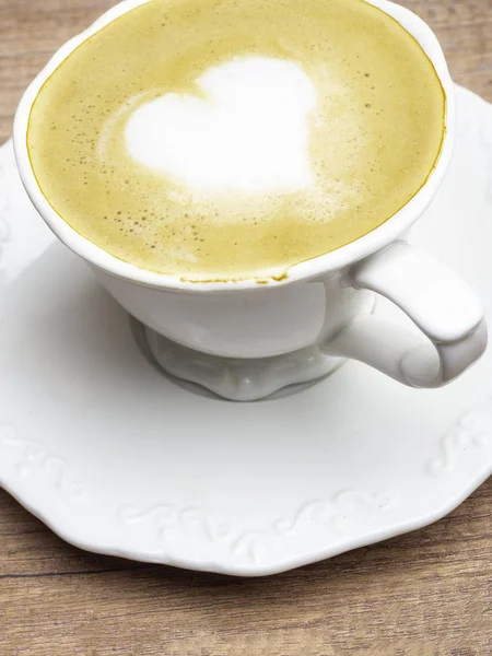 Copa de café blanco vintage con forma de corazón arte latte en mesa de madera . — Foto de Stock
