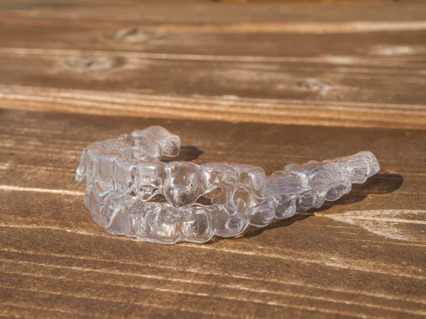 Custodia dentale trasparente o fermo chiaro, apparecchio acustico. Allineatore invisibile sul tavolo in legno — Foto Stock