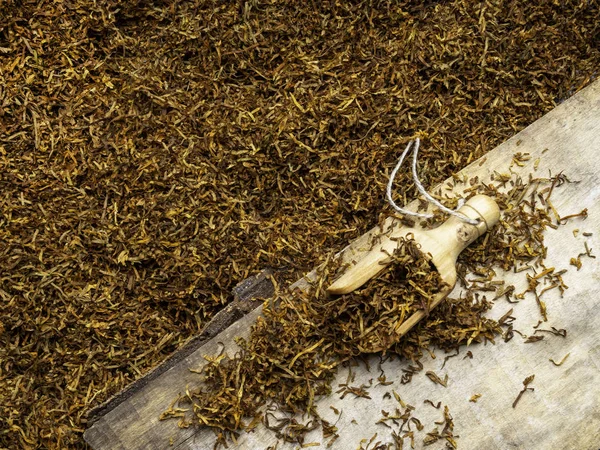 Ξερά φύλλα καπνών σε ξύλινη σανίδα και σε κουτάλι ξύλου — Φωτογραφία Αρχείου