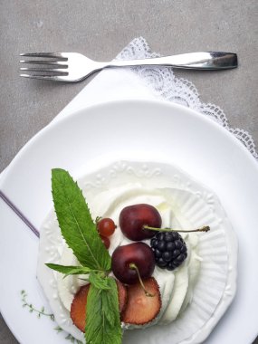 Taze çilek ile Pavlova beze kek, çatal ile beyaz tabakta nane