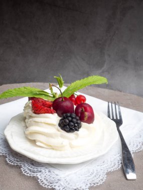 Taze çilek, kiraz, böğürtlen, nane ve krem şanti beton arka plan üzerinde Rustik Pavlova kek.