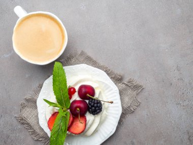 Bir fincan kahve ile kahvaltı, tatlı tatlı Pavlova. Düz döşeme, üst görünüm