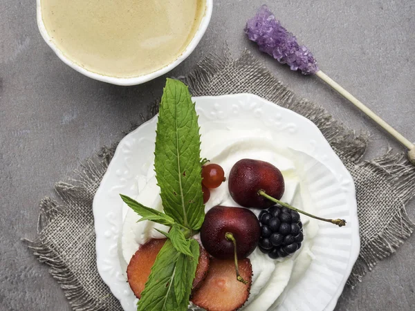 Merengue pastel de postre Pavlova con bayas frescas en un plato y una taza de café. Fondo de piedra, primer plano — Foto de Stock