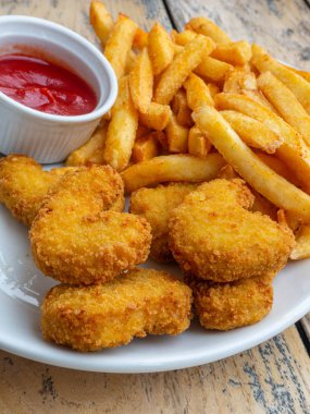 Taze patates kızartması ve tavuk nuggets ahşap masada domates sosu ile servis