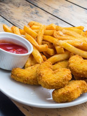 Kızarmış gevrek tavuk nuggets ve beyaz ahşap tahta üzerinde ketçap ile patates kızartması