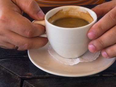 Tahta, vintage bir arka planda bir fincan kahve tutan adam. Elinde bir fincan kahve tutan genç işadamı. Vintage tonları.