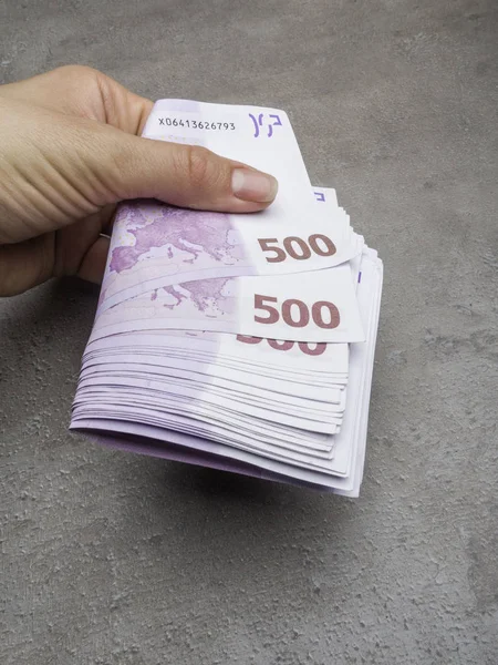 hand giving 500 euro banknotes isolated on grey