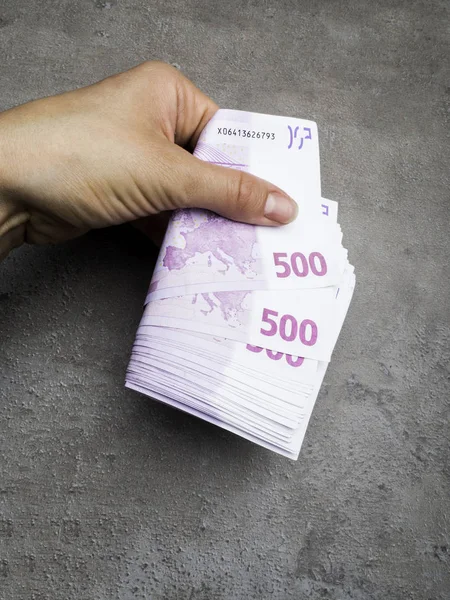 hand giving 500 euro banknotes isolated on grey