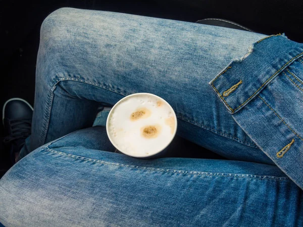 Young drinking coffee take away with legs in jeans on car - Travel ,road trip and winter concept