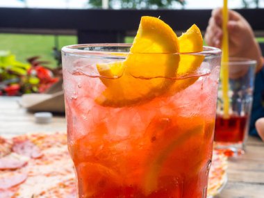 Limon ve portakal dilimleri ile kırmızı coctail ve buz küpleri