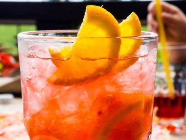 Limon ve portakal dilimleri ile kırmızı coctail ve buz küpleri