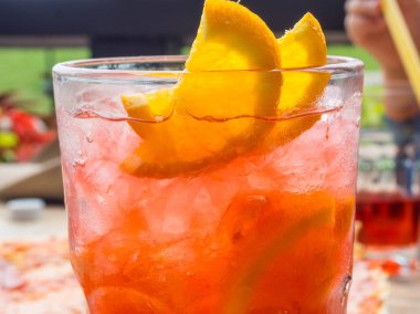 Limon ve portakal dilimleri ile kırmızı coctail ve buz küpleri