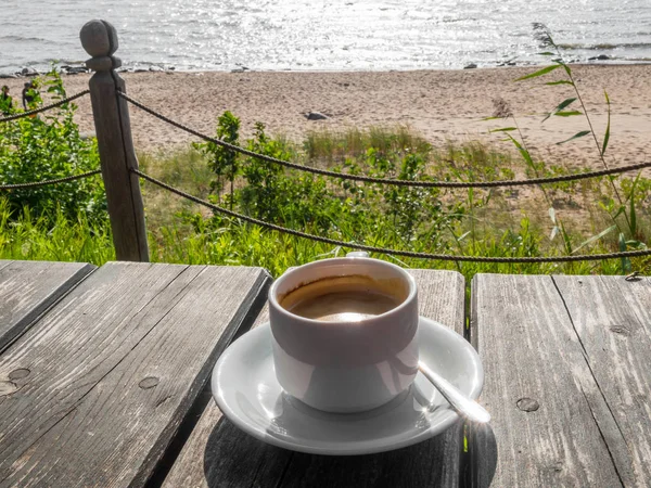 Kuppi kahvia puupöydällä, näkymä merelle. Kesäloma käsite — kuvapankkivalokuva
