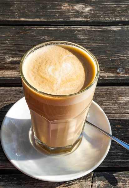Glas Kaffeelatte mit schöner Herzform, Holztisch — Stockfoto