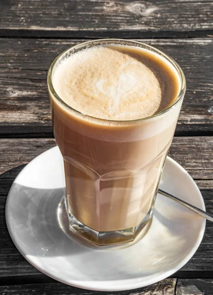 Szklany kubek kawy latte z pięknym kształcie serca, drewniany stół — Zdjęcie stockowe