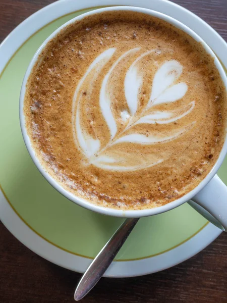 Nahaufnahme weiße Kaffeetasse mit Form Latte-Art-Schaum auf Holztisch. — Stockfoto