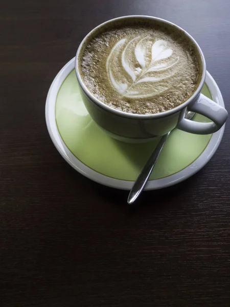 Закрыть белый кофе чашку с формой латте искусства пены на деревянный стол . — стоковое фото