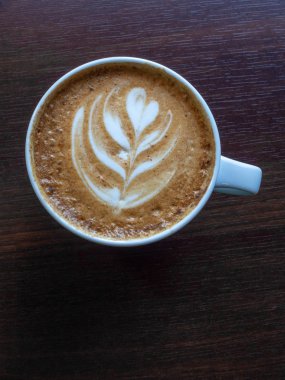 Ahşap masa arka plan köpük süt güzel latte sanat ile bir fincan sıcak kahve. Köpük köpük lü Cappuccino veya latte