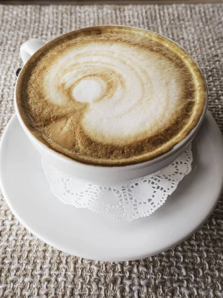 Capuchino caliente con espuma y patrón sobre fondo de paño, una vista lateral — Foto de Stock