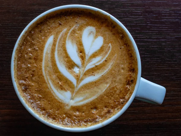 Café caliente en una taza con leche espuma hermoso arte latte sobre fondo de mesa de madera. Cappuccino o latte con espuma espuma — Foto de Stock