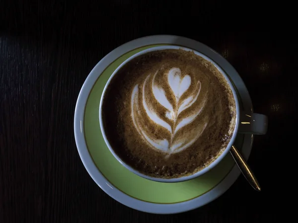 Gorąca kawa w filiżance z piankowym mlekiem piękne Latte Art na drewnianym tle stołu. Cappuccino lub Latte Art, stonowane — Zdjęcie stockowe