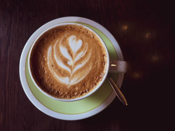 Café caliente en una taza con leche espuma hermoso arte latte sobre fondo de mesa de madera. Arte capuchino o latte, Tonificado — Foto de Stock