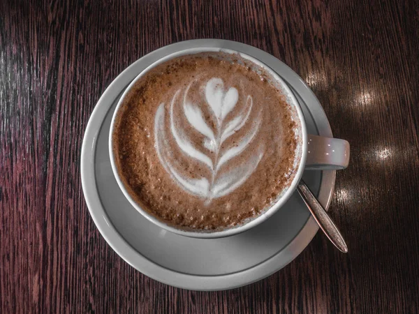 Café caliente en una taza con leche espuma hermoso arte latte sobre fondo de mesa de madera. Arte capuchino o latte, Tonificado — Foto de Stock