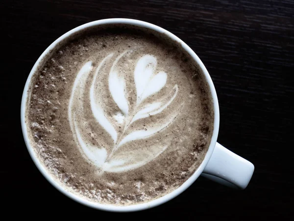 Cerrar taza de café capuchino caliente con forma de corazón arte latte en la mesa de madera en la cafetería, filtro de tono — Foto de Stock