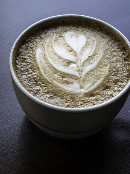 Cerrar taza de café capuchino caliente con forma de corazón arte latte en la mesa de madera en la cafetería, filtro de tono — Foto de Stock