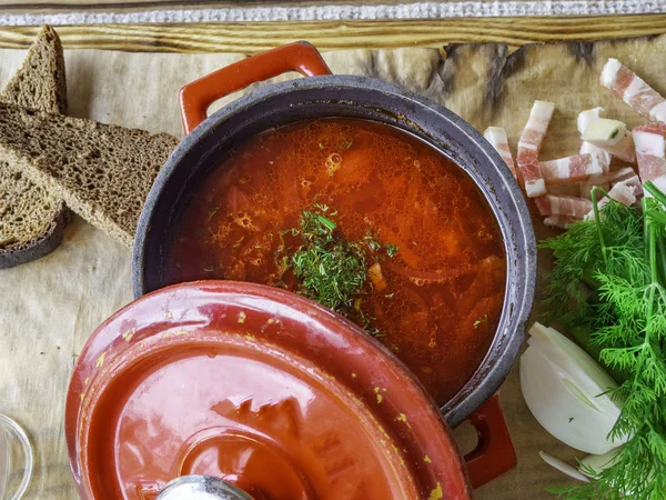 Foto für Speisekarte, russischer Borschtsch im roten Topf mit saurer Sahne Knoblauch, Brot, Petersilie, Dill, Schmalz, ukrainischer Borschtsch mit saurer Sahne, Lebensmittelhintergrund, Lebensmittel und Gesundheit — Stockfoto