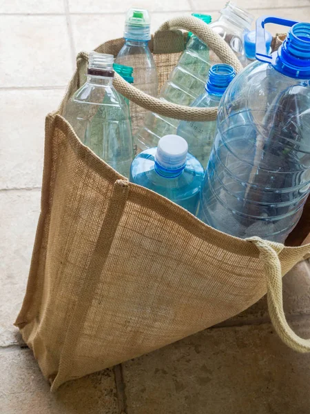 Botella de plástico en bolsa de arpillera. Reciclaje reutilizable artículos de uso diario alternativos a desechables. Estilo de vida ecológico y concepto de cero residuos . — Foto de Stock