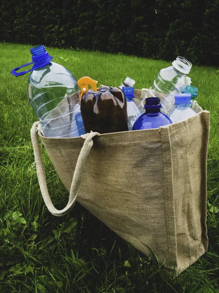 Bolsa de arpillera ecológica y botellas de plástico en el interior. Concepto de compra cero residuos . — Foto de Stock