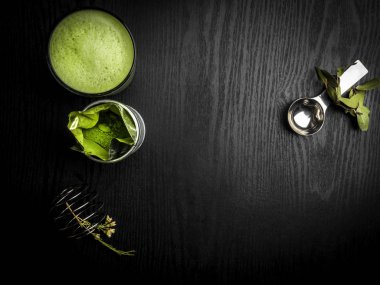 Yeşil yaprakları ve metal kaşık, çırpma teli, antioksidanlar zengin içecek, metin için boş alan ile sıcak yeşil çay latte