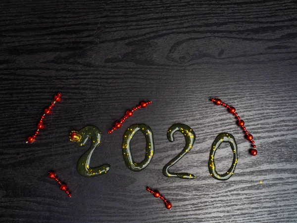 Greeting card Happy New Year 2020. Beautiful Wide Angle creative holiday web banner or billboard with Golden sequins, red garlands, inscription from slime 2020 written sparklers on wooden background