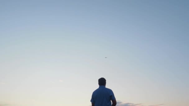 Ung Man Tittar Och Navigerar Flygande Drönare Blå Klar Himmel — Stockvideo