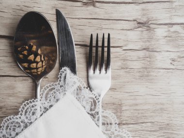 Şenlikli Tebrik Kartı Kış tatil yemek kaşığı, çatal, beyaz peçete üzerinde bıçak beyaz ahşap arka plan üzerinde koni ile süslenmiş, kopya alanı