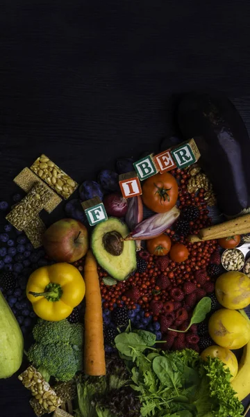 Foods rich in fiber as bread sticks, wheat, white beans, lentils, spinach, nuts, seed, pears, bananas, berries, avocado, plums, eggplant, broccoli, onion, tomatoes, Wooden table as background