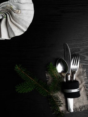 Dekor olarak havlu, çuval bezi ve yeşil dalı ile Noel masa ayarı, ahşap tahta üzerinde gümüş. Üstte görüntü.