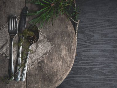 Dekor olarak havlu, çuval bezi ve yeşil dalı ile Noel masa ayarı, ahşap tahta üzerinde gümüş. Üstte görüntü.