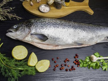 Somon balığı. Çiğ somon balık siyah ahşap masada pişirmeiçin malzemelerle bütün. Üstte görüntü