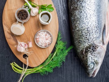 Koyu arka plan üzerinde malzemelerle taze pişmemiş somon. Sağlık kavramı. Diyet. Omega açısından zengin balıklar