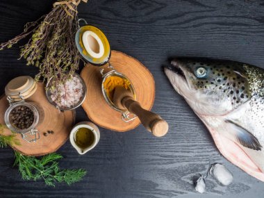 Zerdeçal, tuz, biber, kekik, dereotu, sürahi yağ, üst görünümü gibi pişirme maddeleri ile masada taze çiğ somon ile Kompozisyon