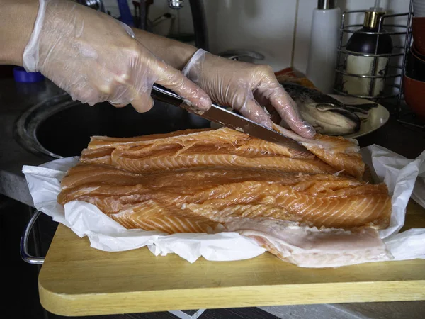 Pulendo e filettando un pesce fresco con filetto, filettando un salmone in deposito di pesce — Foto Stock