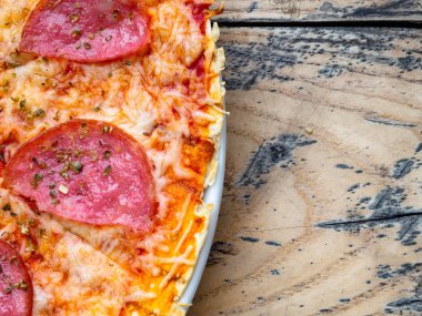 Bütün salamlı pizza ahşap bir masa dilimlenmiş