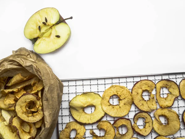 Tasty dried apples chips in paper bag and metal tray isolated on white background, free space for text