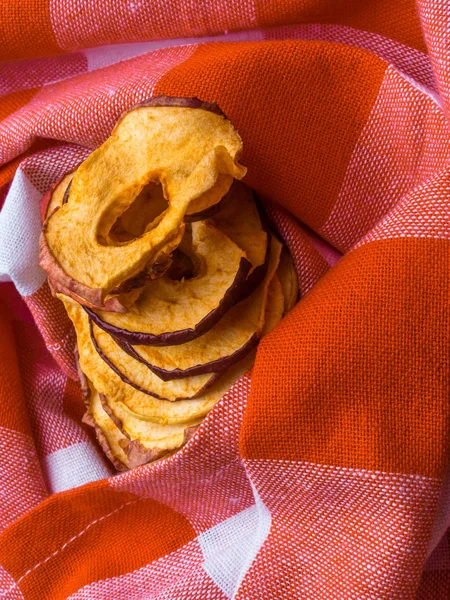 Close up of organic apple chips slices on kitchen orange towel. Healthy vegetarian fruit snack — Stock Photo, Image