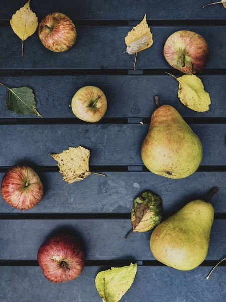 Manzanas y peras frescas en la temporada de otoño, hojas amarillas y verdes en la mesa de jardín — Foto de Stock