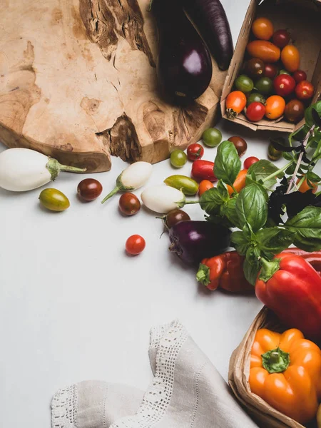 Beyaz masada eko kağıt torbalarda çiğ sebze . taze domates, fesleğen, patlıcan, biber görünümü. Sağlıklı beslenme konsepti.