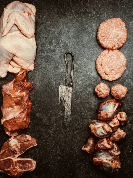 Mixed types of raw fresh meat on cutting board with knife — Stock Photo, Image