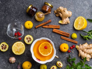 Limon, kızılcık, kavanozlarda farklı bal, cydonia, tarçın beton arka plan üzerinde sopa ile zencefil çayı Fincan